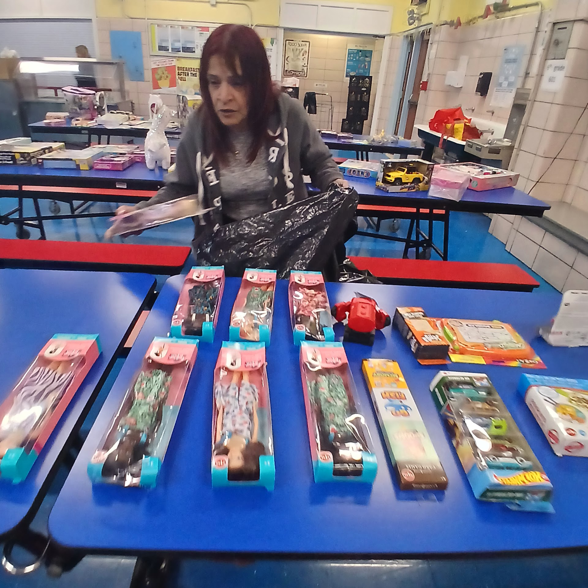 Volunteer sorting dolls and toys on tables for a holiday distribution
