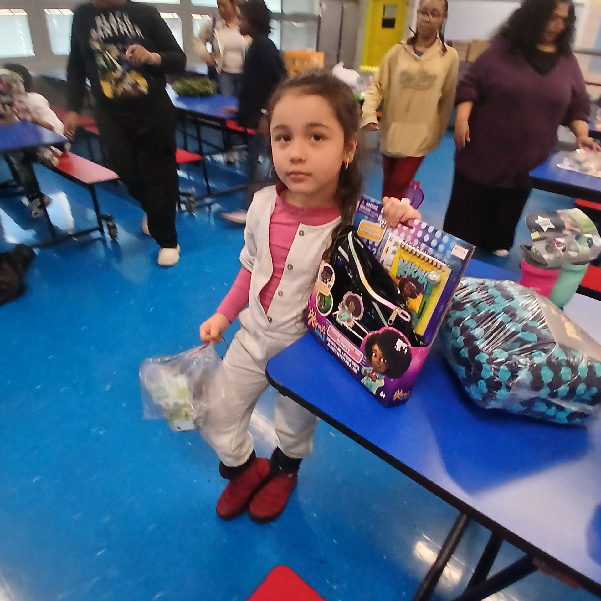 Child holding a backpack and activity items after gift pickup